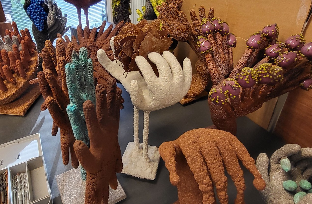 Sculpturen in de vorm van handen, met uiteenlopende kleuren en oppervlaktestructuren.